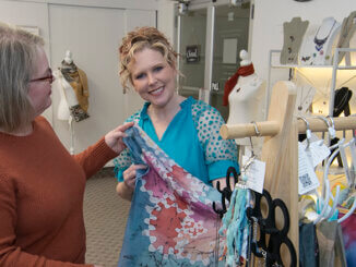 Carrie Wright (L) shows Angie Hibner (R) some of her handpainted silk scarves. Photo by Mike Rhodes