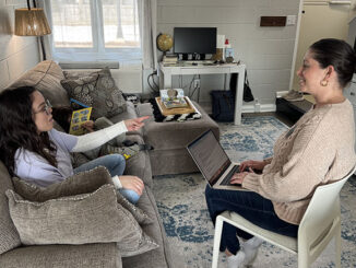 Muncie Scholar House Director, Ashley Soldaat (right), converses with a Muncie Scholar in her student apartment, while her young son reads a book. Photo provided.